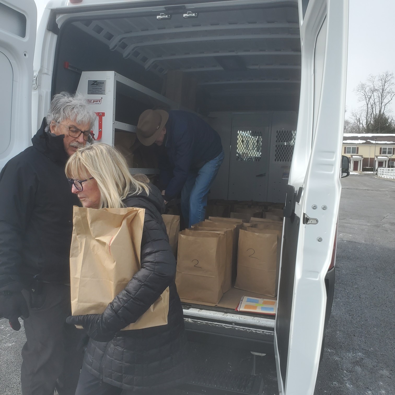 Doug Roberts and Bobbie Doak carry bags from the van to doorsteps.